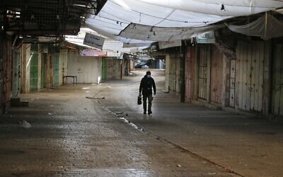 A street coffee vendor walks by closed shops amid the COVID-19 pandemic, in the West Bank town of Hebron on December 11, 2020 (HAZEM BADER / AFP)