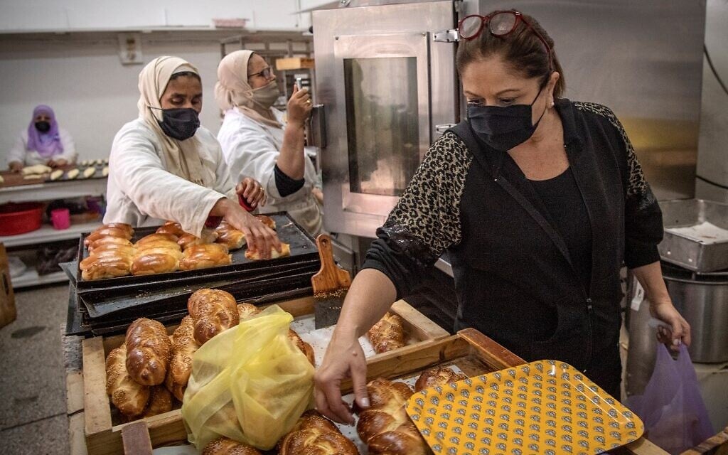 A Moroccan Jewish woman (R) fills bags with pastries to serve customers at the  kosher bakery 'Madame Fhal' in the western Moroccan port city of Casablanca, on December 11, 2020. (FADEL SENNA / AFP)