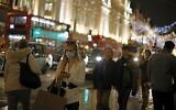 Shoppers pass under the Christmas lights on Regents Street in central London on December 14, 2020. (Tolga Akmen/AFP)