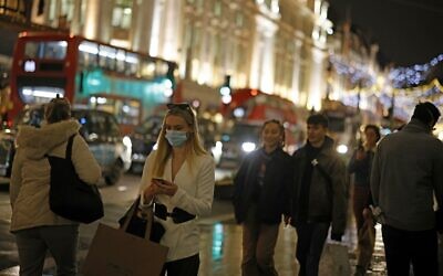 Shoppers pass under the Christmas lights on Regents Street in central London on December 14, 2020. (Tolga Akmen/AFP)