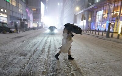 A person holds an umbrella as she walks under the snow in Times Square in New York City, December 16, 2020, as Storm Gail hits the East coast. (Timothy A. Clary/AFP)