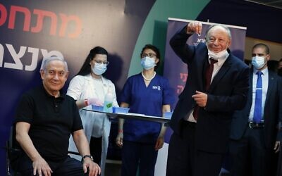 Prime Minister Benjamin Netanyahu smiles before receiving a coronavirus vaccine at Sheba Medical Center in Ramat Gan from his personal physician, Dr. Tzvi Berkovitz. Netanyahu, 71, followed by Health Minister Yuli Edelstein, became the first Israelis to get the vaccine. (AMIR COHEN / POOL / AFP)