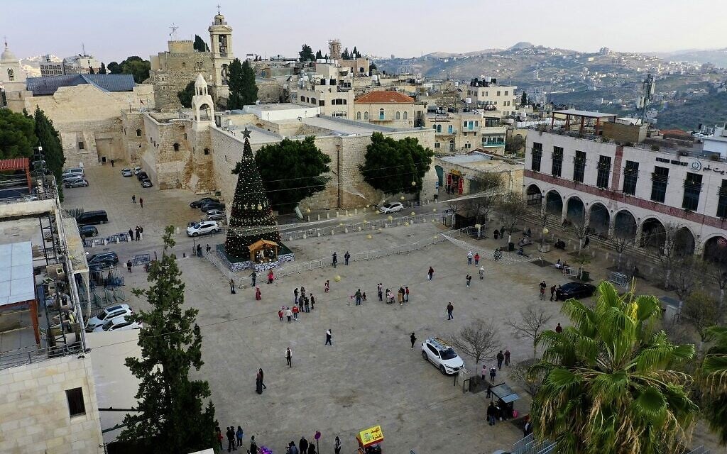 Locals visiting the Christmas tree in front of the Church of the Nativity, in the West Bank city of Bethlehem, December 22, 2020. (HAZEM BADER / AFP) Locals visiting the Christmas tree in front of the Church of the Nativity, in the West Bank city of Bethlehem, December 22, 2020. (HAZEM BADER / AFP)