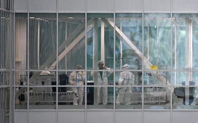 Medical workers are seen in a passageway between the buildings of a hospital in Kommunarka, where patients suffering from the coronavirus disease are treated, on the outskirts of Moscow on December 25, 2020. (NATALIA KOLESNIKOVA / AFP)