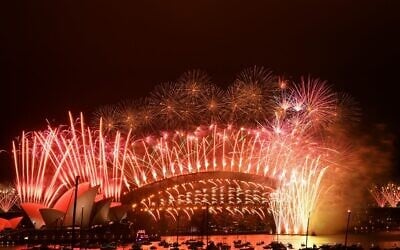 New Year's Eve fireworks erupt over Sydney's iconic Harbour Bridge and Opera House (L) during the fireworks show on January 1, 2021. (Photo by SAEED KHAN / AFP)