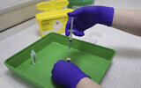 A UK National Health Service pharmacy technician at the Royal Free Hospital, simulates the preparation of the Pfizer vaccine to support staff training ahead of the rollout, in London, December 4, 2020. (Yui Mok/Pool Photo via AP)