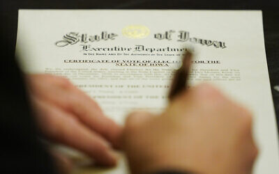 A member of Iowa's Electoral College signs the Certificate of Vote of Electors for the State of Iowa, December 14, 2020, at the Statehouse in Des Moines, Iowa. (AP Photo/Charlie Neibergall)