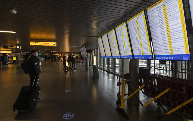Illustrative: A traveler wearing a face mask checks the flight departures at Schiphol Airport, near Amsterdam, Netherlands. December 18, 2020. (AP Photo/Peter Dejong) Illustrative: A traveler wearing a face mask checks the flight departures at Schiphol Airport, near Amsterdam, Netherlands. December 18, 2020. (AP Photo/Peter Dejong)