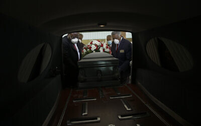 Mortician Cordarial O. Holloway, foreground left, funeral director Robert L. Albritten, foreground right, and funeral attendants Eddie Keith, background left, and Ronald Costello place a casket into a hearse in Dawson, Georgia, April 18, 2020. (AP Photo/Brynn Anderson)