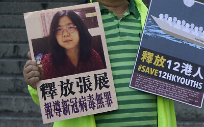 A pro-democracy activist holds placards with the picture of Chinese citizen journalist Zhang Zhan outside the Chinese central government's liaison office, in Hong Kong, Monday, Dec. 28, 2020. Zhang, a former lawyer and citizen journalist from Shanghai, has been sentenced to four years in prison for her reporting on the initial coronavirus outbreak in Wuhan, China. The activists demand the releases of Zhang, as well as the 12 Hong Kong activists detained at sea by Chinese authorities. (AP Photo/Kin Cheung)