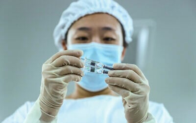 A staff member inspects syringes of COVID-19 inactivated vaccine products at a packaging plant of the Beijing Biological Products Institute Co., Ltd, a unit of state-owned Sinopharm in Beijing, December 25, 2020. (Zhang Yuwei/Xinhua via AP)