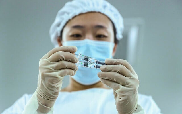 A staff member inspects syringes of COVID-19 inactivated vaccine products at a packaging plant of the Beijing Biological Products Institute Co., Ltd, a unit of state-owned Sinopharm in Beijing, December 25, 2020. (Zhang Yuwei/Xinhua via AP)