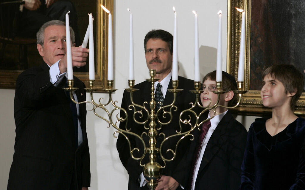 US President George W. Bush lights a Menorah during a Hanukkah reception, as Rabbi Joshua Skoff, second left,  Jared Skoff, and Eden Skoff look on at the White House on December 6, 2005 in Washington. (AP/Evan Vucci)