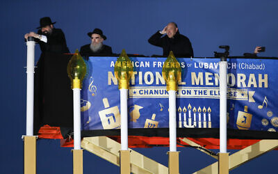 From left, Rabbi Levi Shemtov, with Rabbi Abraham Shemtov and National Economic Director Gary Cohn, struggles in the wind to light the Menorah during the annual National Menorah Lighting, in celebration of Hanukkah, on the Ellipse near the White House in Washington, Tuesday, Dec. 12, 2017. (AP Photo/Carolyn Kaster)