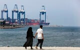 A couple walk in front of the Red Sea port city of Jiddah, Saudi Arabia, Friday, Oct. 11, 2019.  (AP Photo/Amr Nabil)