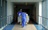 In this May 14, 2020 photo, medical staff transfer a patient through a corridor at the Royal Blackburn Teaching Hospital, in Blackburn, England, amid the coronavirus pandemic. (Hannah McKay/Pool Photo via AP)