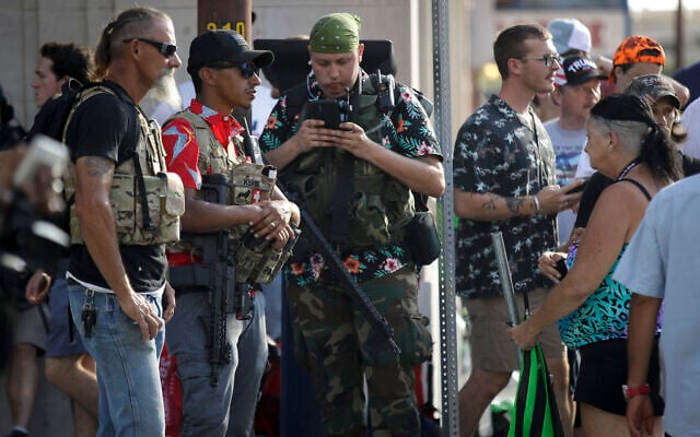 Illustrative: Gun-carrying men wearing the Hawaiian print shirts associated with the Boogaloo movement watch a demonstration near the BOK Center where US President Donald Trump will hold a campaign rally in Tulsa, Oklahoma, June 20, 2020. (AP Photo/Charlie Riedel) Illustrative: Gun-carrying men wearing the Hawaiian print shirts associated with the Boogaloo movement watch a demonstration near the BOK Center where US President Donald Trump will hold a campaign rally in Tulsa, Oklahoma, June 20, 2020. (AP Photo/Charlie Riedel)