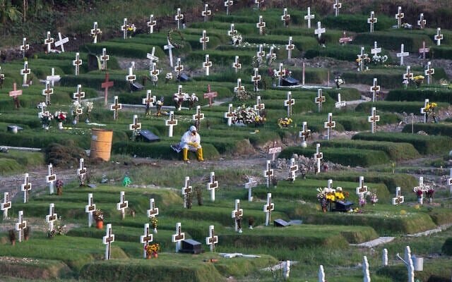 A worker in protective suits takes a break amid graves at a newly opened cemetery for the victims of COVID-19 in Medan, North Sumatra, Indonesia, November 16, 2020. (Binsar Bakkara/AP) A worker in protective suits takes a break amid graves at a newly opened cemetery for the victims of COVID-19 in Medan, North Sumatra, Indonesia, November 16, 2020. (Binsar Bakkara/AP)