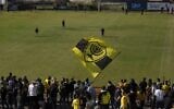 Beitar Jerusalem soccer supporters sing and wave their flag as players enter the pitch during a team training session in Jerusalem, December 11, 2020. (AP Photo/Maya Alleruzzo)