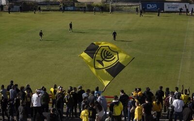 Beitar Jerusalem soccer supporters sing and wave their flag as players enter the pitch during a team training session in Jerusalem, December 11, 2020. (AP Photo/Maya Alleruzzo)