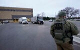 A US marshal watches as trucks loaded with the Pfizer-BioNTech COVID-19 vaccine leave the Pfizer Global Supply Kalamazoo manufacturing plant in Portage, Michigan, December 13, 2020. (Morry Gash/AP)