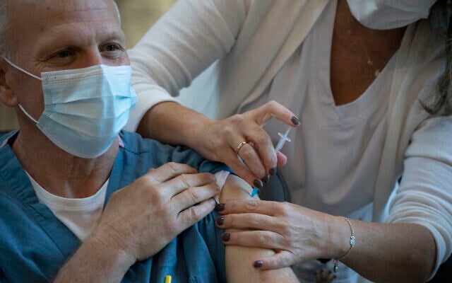 A medical staff member receives a COVID-19 coronavirus vaccine at the Ichilov Hospital in Tel Aviv, Israel,  Dec. 20, 2020. (AP Photo/Ariel Schalit)