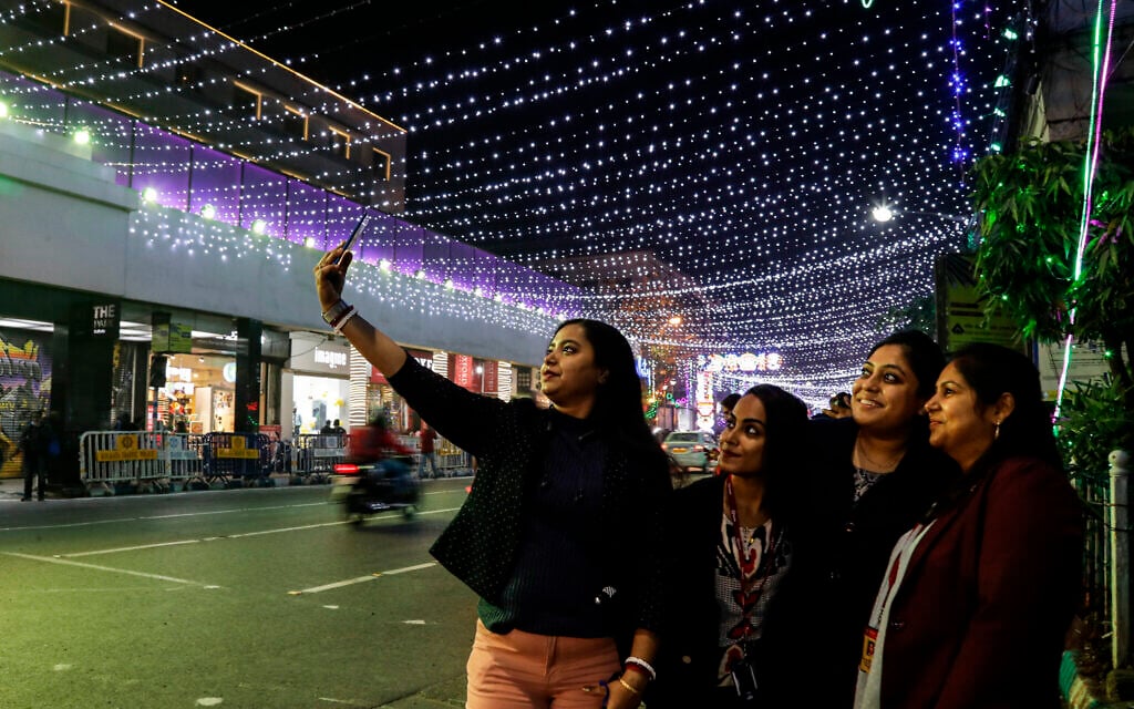 A group of Indian women take a selfie on a mobile phone in a street decorated ahead of Christmas in Kolkata, India, Tuesday, December 22, 2020. (AP Photo/Bikas Das)