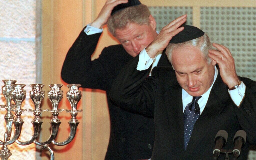 Prime Minister Benjamin Netanyahu and President Clinton put on yarmulkes before lighting a Hanukkah candle during a state dinner held on December 13, 1998, in Jerusalem, in honor of the visiting president. (AP/Zoom 77)