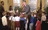 Screen capture from 1993 video showing US President Bill Clinton grabbing Ilana Kattan's hair to stop it from burning after noticing that it had caught fire on the menorah her class had just helped him light at the White House. (Clinton Presidential Library on YouTube via JTA)