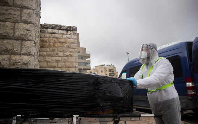 Chevra Kadisha workers wearing protective clothing carry the body of a patient who died from complications of COVID-19 at the Shamgar Funeral Home in Jerusalem on April 1, 2020 (Yonatan Sindel/Flash90) Chevra Kadisha workers wearing protective clothing carry the body of a patient who died from complications of COVID-19 at the Shamgar Funeral Home in Jerusalem on April 1, 2020 (Yonatan Sindel/Flash90)