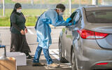 Health care workers take samples at a mobile testing station, in Lod, on December 1, 2020 (Yossi Aloni/Flash90)