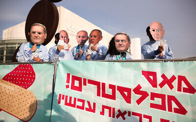 Israeli activists wear masks of Prime Minister Benjamin Netanyahu, Defense Minister Benny Gantz and Finance Minister Israel Katz as they protest against the government, at Habima Square in Tel Aviv, December 2, 2020. (Miriam Alster/Flash90)