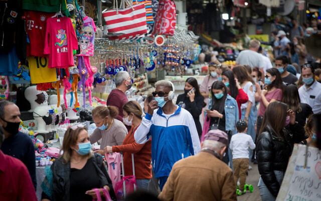 People wear protective masks at the Carmel market in Tel Aviv, on December 13, 2020. (Miriam Alster/FLASH90) People wear protective masks at the Carmel market in Tel Aviv, on December 13, 2020. (Miriam Alster/FLASH90)