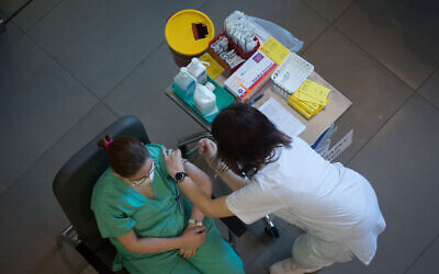 An Israeli medical worker receives a COVID-19 vaccine at Ichilov Hospital in Tel Aviv on December 20, 2020. (Miriam Alster/Flash90)
