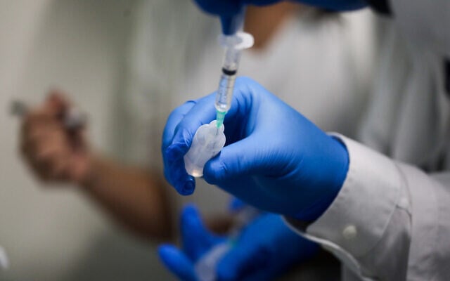 An Israeli medical worker holds a COVID-19 vaccine at Tel Aviv's Sourasky Medical Center on December 20, 2020 (Miriam Alster/Flash90)