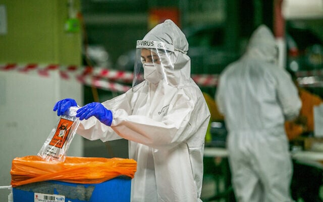 A Maccabi Healthcare Services worker handles a test sample at a coronavirus testing site in Modiin, on December 24, 2020. (Yossi Aloni/Flash90) A Maccabi Healthcare Services worker handles a test sample at a coronavirus testing site in Modiin, on December 24, 2020. (Yossi Aloni/Flash90)