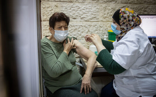 A woman receives a COVID-19 vaccine at a Clalit clinic in Jerusalem on December 24, 2020. (Yonatan Sindel/Flash90) A woman receives a COVID-19 vaccine at a Clalit clinic in Jerusalem on December 24, 2020. (Yonatan Sindel/Flash90)