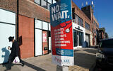 A man walks past a sign advertising the services of ParCare Community Health Care Network in front of the company's facility in the Williamsburg neighborhood of the Brooklyn borough of New York, December 27, 2020. (AP Photo/Kathy Willens)