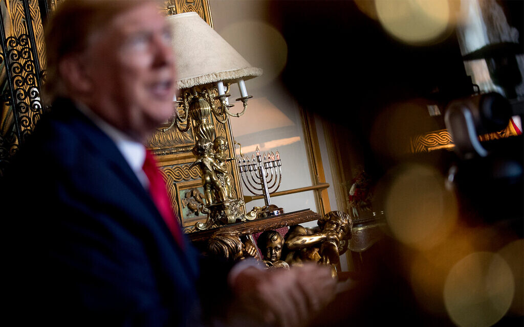An electric menorah is visible behind US President Donald Trump as he speaks to members of the media following a Christmas Eve video teleconference with members of the military at his Mar-a-Lago estate in Palm Beach, Florida, Dec. 24, 2019. (AP Photo/Andrew Harnik)