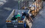 A man searches in a garbage container in downtown Jerusalem, August 17, 2020. (Yonatan Sindel/Flash90)