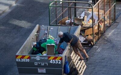 A man searches in a garbage container in downtown Jerusalem, August 17, 2020. (Yonatan Sindel/Flash90)