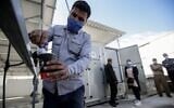 A Palestinian man fills a cup of water from a solar-powered water generator that extracts potable water straight from the air donated by Watergen, a company owned by a Russian-Israeli businessman, in the town of Khan Yunis in the southern Gaza Strip, on November 16, 2020 (SAID KHATIB / AFP)
