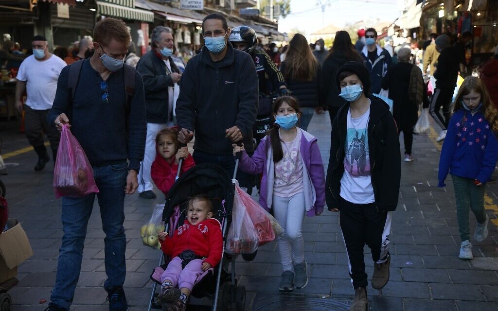 A family walks in the Mahane Yehuda market in Jerusalem on December 27, 2020. (MENAHEM KAHANA/AFP)