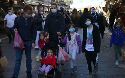 A family walks in the Mahane Yehuda market in Jerusalem on December 27, 2020. (MENAHEM KAHANA/AFP)