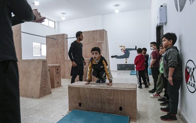 A coach trains Palestinian children at the Wallrunners Parkour Academy's training facility in Gaza City on December 28, 2020. (MAHMUD HAMS / AFP)