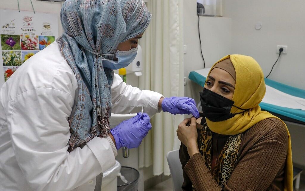 A Palestinian resident of East Jerusalem's Beit Hanina neighborhood gets vaccinated against the coronavirus at a Clalit Health Services clinic there, on January 12, 2021. (Ahmad Gharabli/AFP) A Palestinian resident of East Jerusalem's Beit Hanina neighborhood gets vaccinated against the coronavirus at a Clalit Health Services clinic there, on January 12, 2021. (Ahmad Gharabli/AFP)
