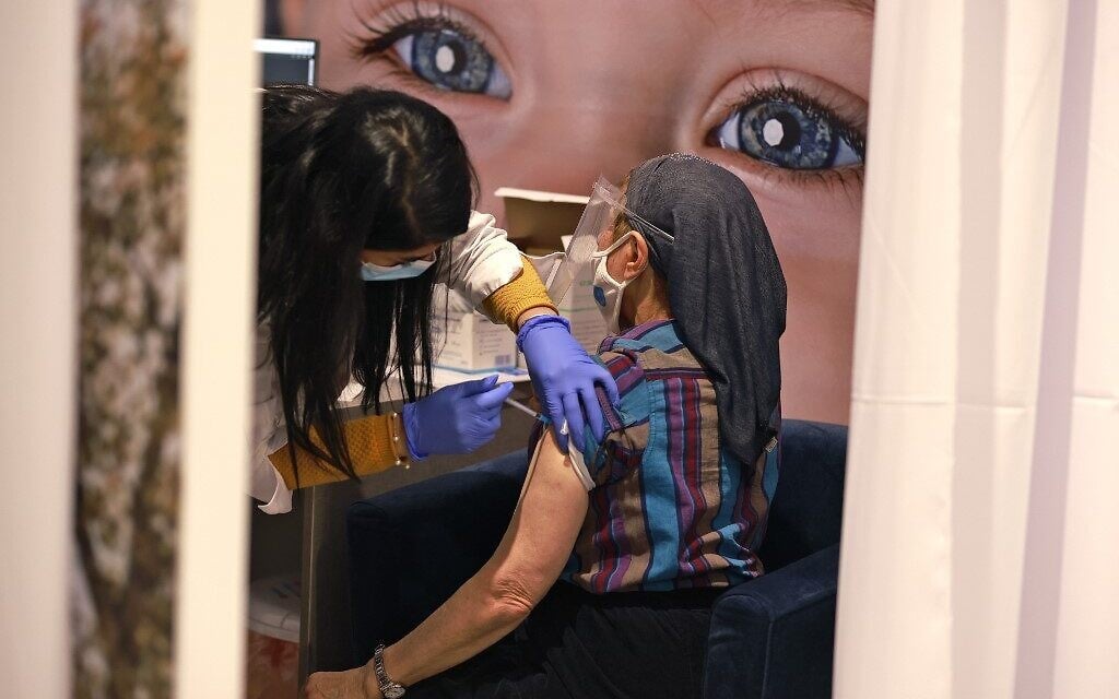 An Israeli woman gets vaccinated against the COVID-19 coronavirus at the Kupat Holim Meuhedet clinic vaccination centre in Jerusalem, on January 12, 2021. (MENAHEM KAHANA / AFP) An Israeli woman gets vaccinated against the COVID-19 coronavirus at the Kupat Holim Meuhedet clinic vaccination centre in Jerusalem, on January 12, 2021. (MENAHEM KAHANA / AFP)