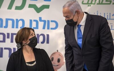 Prime Minister Benjamin Netanyahu speaks to an unidentified woman during his visit to a coronavirus vaccination facility in the northern Israeli Arab city of Nazareth, on January 13, 2021. (Gil Eliyahu/Pool/AFP)