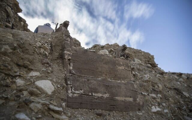 Visitors walk past a wooden sarcophagus which is still buried, during the official announcement of the discovery by an archaeological mission he leads of a new trove of treasures at Egypt's Saqqara necropolis south of Cairo, on January 17, 2021. (Khaled DESOUKI / AFP)