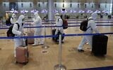 Passengers wearing full protective suits and masks to protect against the COVID-19 pandemic push their luggage trolleys at the departures area at Ben Gurion Airport on January 19, 2021. (Jack Guez/AFP)